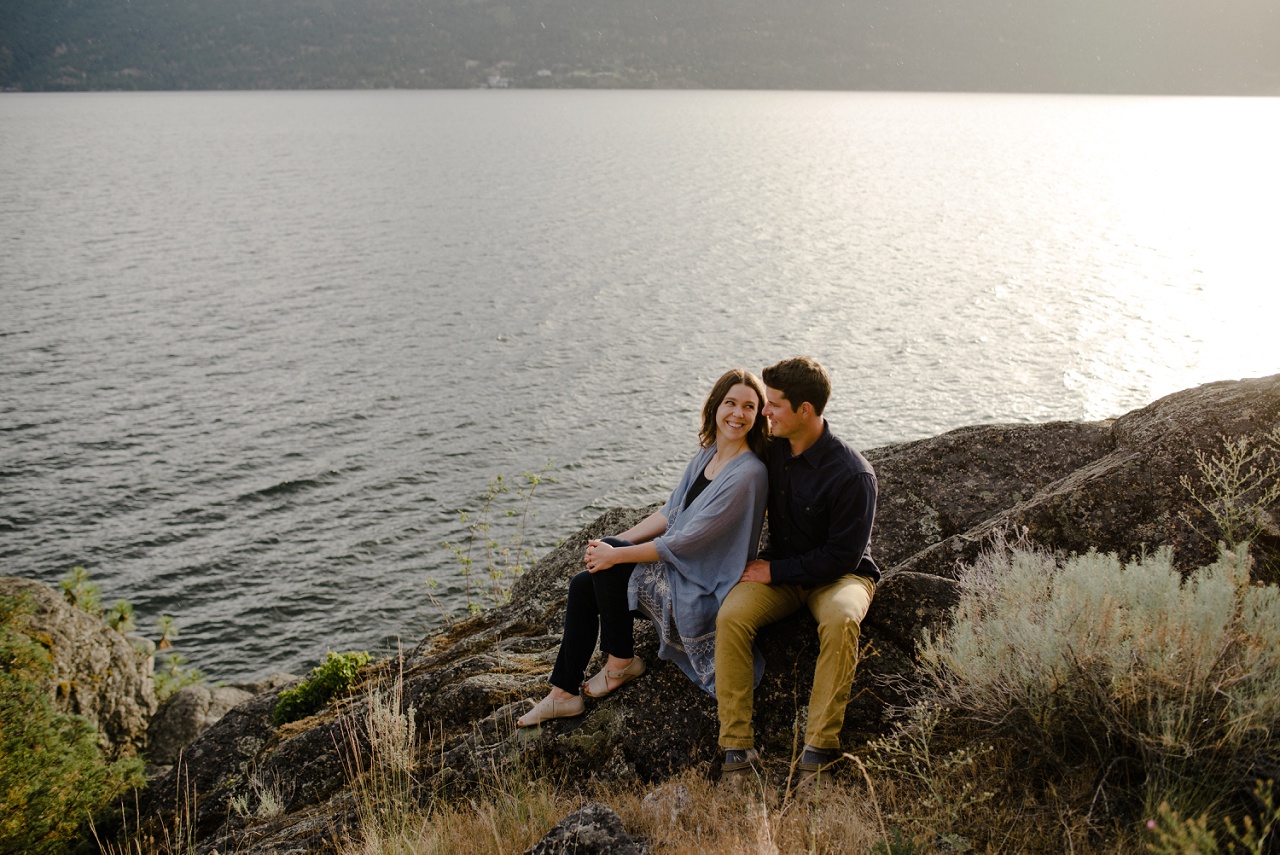 couple smiling for engagement photography over Okanagan Lake